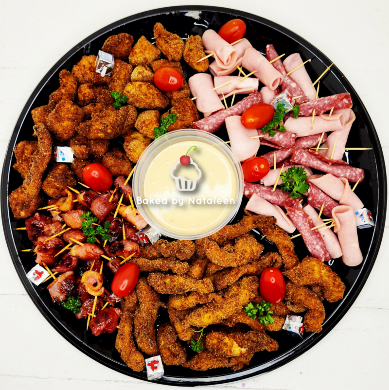 Colorful party platter with breaded fried chicken bites, folded ham and salami skewers, cherry tomatoes, and a central creamy dip labeled Baked by Nataleen.