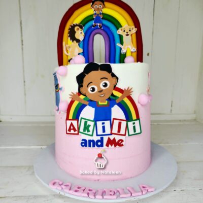 Two-tier birthday cake with a rainbow arch and Akili and Me characters, pink base, and 'Akili and Me' lettering on the front.
