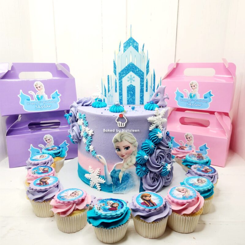 Pastel Frozen-themed birthday cake with Elsa figure, blue and purple frosting, snowflakes, and matching cupcakes for a party.