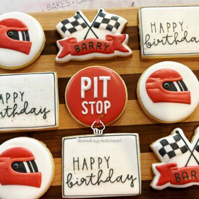 Race-car themed birthday cookies with checkered flags, a Pit Stop sign reading 'BARry', and 'Happy Birthday' messages