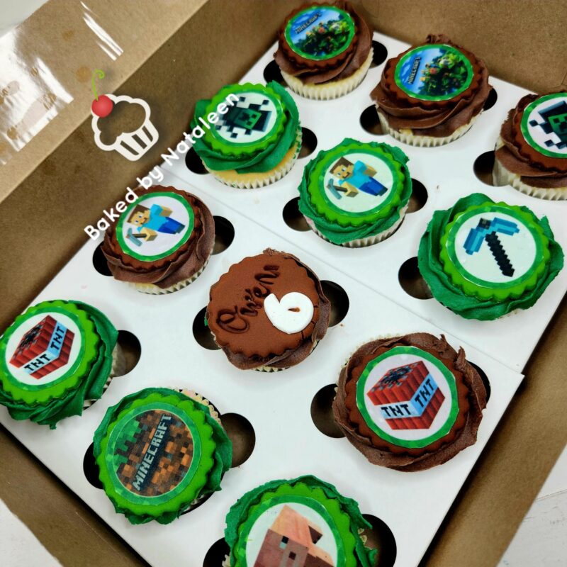 Box of Minecraft-themed cupcakes with green and brown icing and edible toppers in a white boxalk.