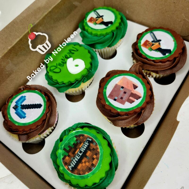 Box of six Minecraft-themed cupcakes with green and brown frosting, each topped with circular edible images (creeper, sword, pickaxe, house, Minecraft logo)