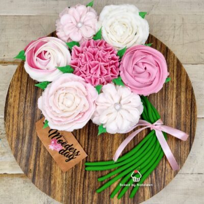 Pastel buttercream flower bouquet arranged on a round wooden board for Mother's Day, tied with a pink ribbon (Baked by Nataleen).