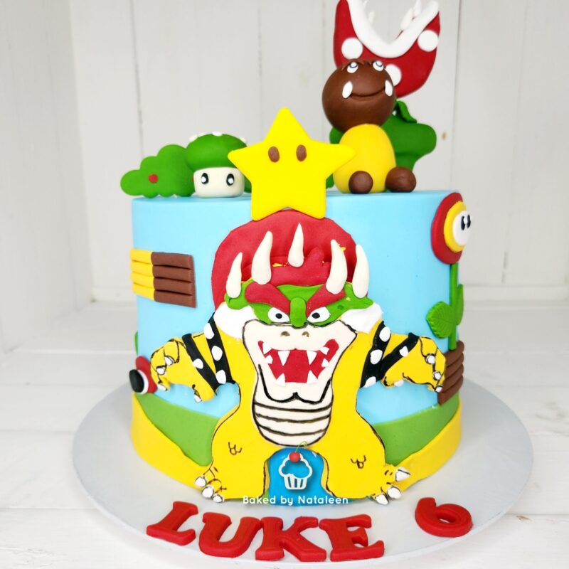 Two-tier birthday cake with Bowser on the front, a bright yellow star on top, and Mario-style decorations; 'LUKE' spelled in red on the base.