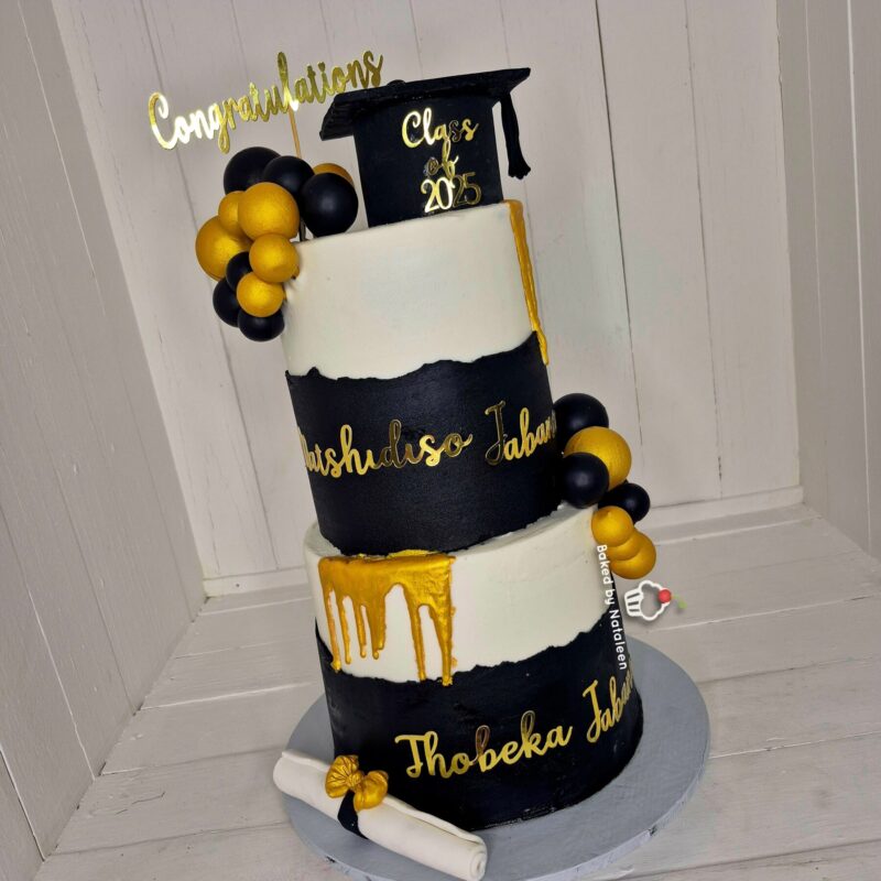 Three-tier black-and-white graduation cake with gold lettering, a mortarboard topper, and black/gold balloon cluster on the side.