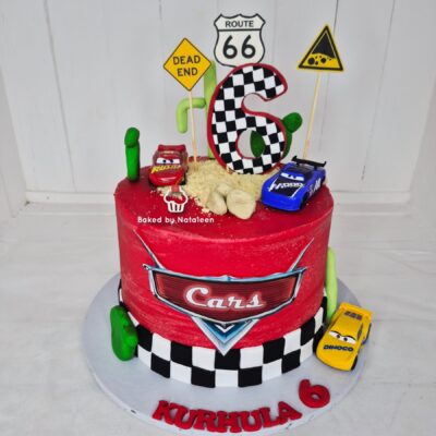 Red Cars-themed birthday cake with a large checkered '6' topper and road signs, Cars logo, toy cars, and 'KURHULA 6' on the base.