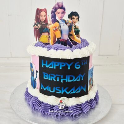 Birthday cake with purple and white frosting and a toppers figurines display reading 'Happy 6th Birthday Muskan' on a black panel with blue lettering, set on a white wooden background.
