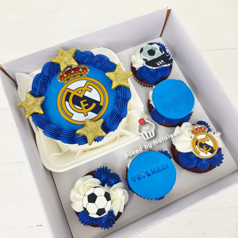 Real Madrid-themed cake with blue frosting and gold stars, plus soccer cupcakes and a blue birthday cookie in a white box cake set