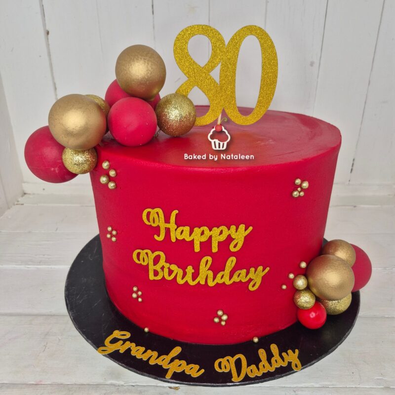 Red birthday cake with gold 'Happy Birthday' lettering, decorated with red and gold balls and a glittery '30' topper, on a black board reading 'Grandpa Daddy'