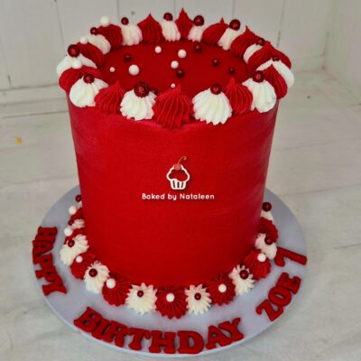 Tall red fondant birthday cake decorated with white and red piped rosettes and berry accents, board reads 'Happy Birthday Zoe'
