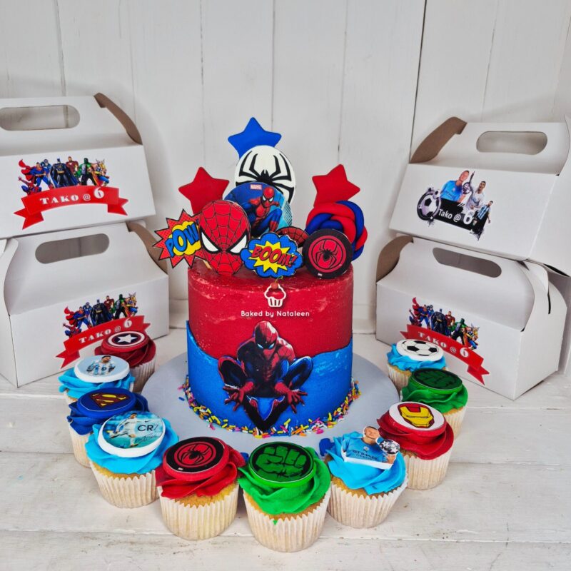 Spider-Man-themed birthday cake with red and blue frosting, comic-style toppers, and surrounding cupcakes with superhero logos and messages.