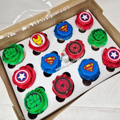 Box of superhero-themed cupcakes with logos: Superman, Spider-Man, Captain America, Hulk fist, arranged in a crate.