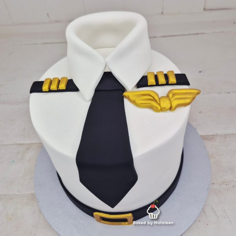 Cake shaped like a pilot’s white shirt with a black tie, gold epaulets, and a wing badge.
