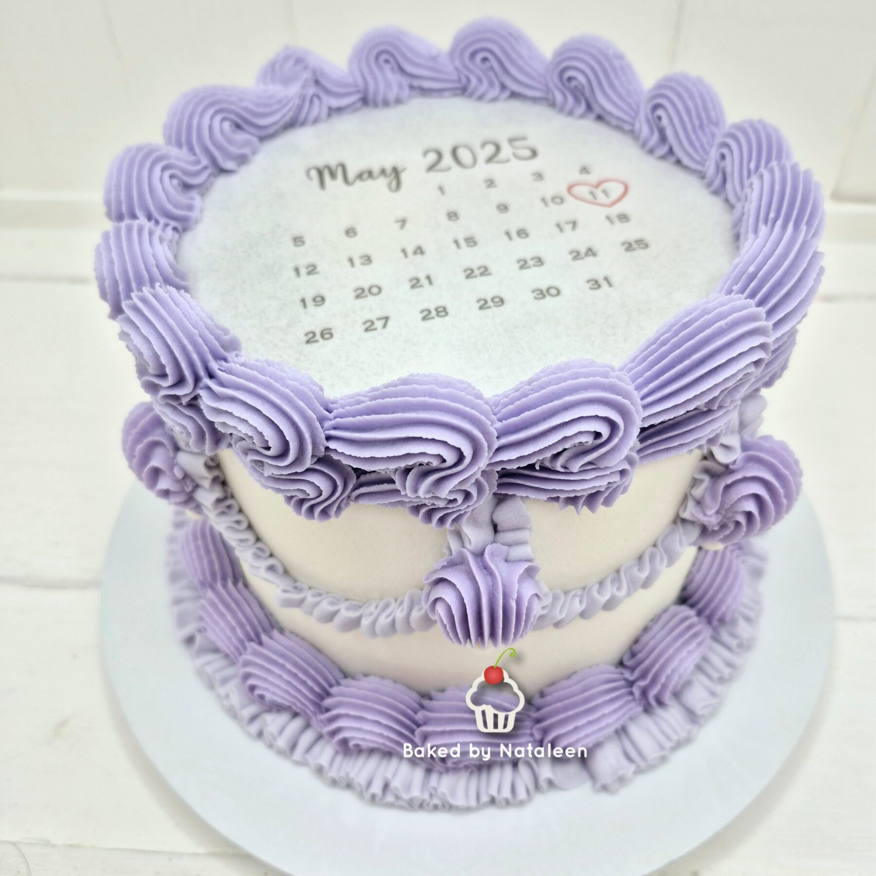 Lavender frosted cake with a rosette edge and a top calendar showing May 2025 with the 11th circled by a heart.