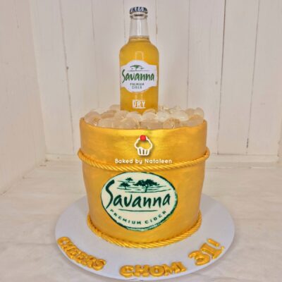 Gold fondant cake with rope trim, topped by a Savanna Premium Cider bottle and ice cubes, featuring a large Savanna logo on the front.