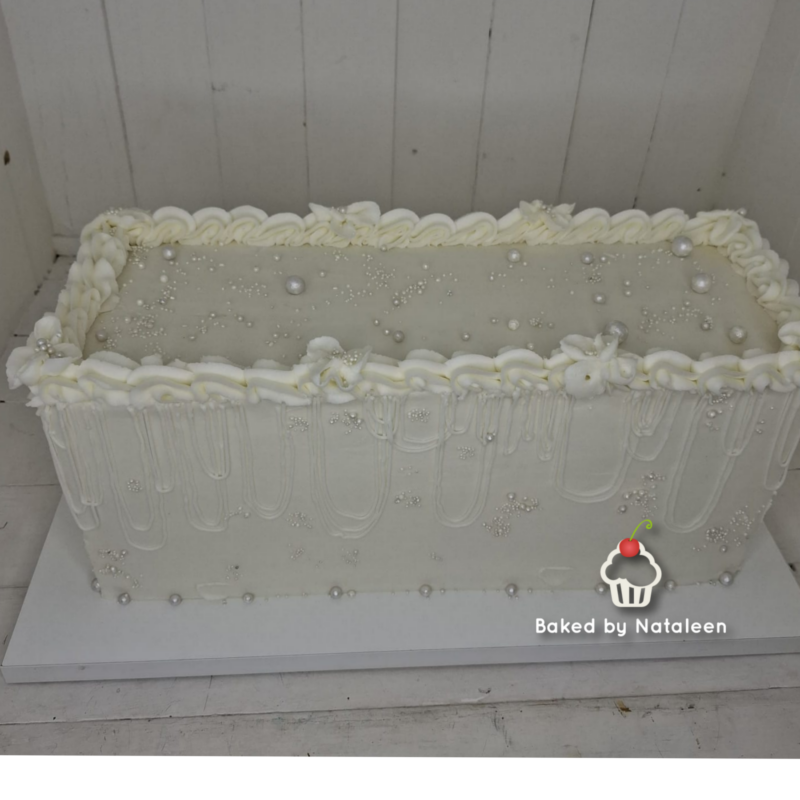 Rectangular white cake with pearl decorations and a ruffled icing border; watermark says 'Baked by Nataleen' with a cupcake icon.