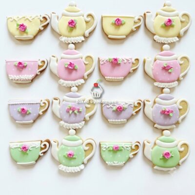 Assorted pastel teapot and teacup cookies decorated with pink roses, arranged in a grid.