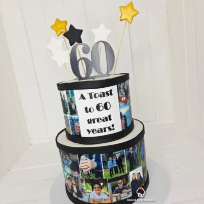 Two-tier black-and-white birthday cake with a photo collage around the sides and a plaque reading, "A Toast to 60 great years!" topped by a large glittery 60 and star picks.
