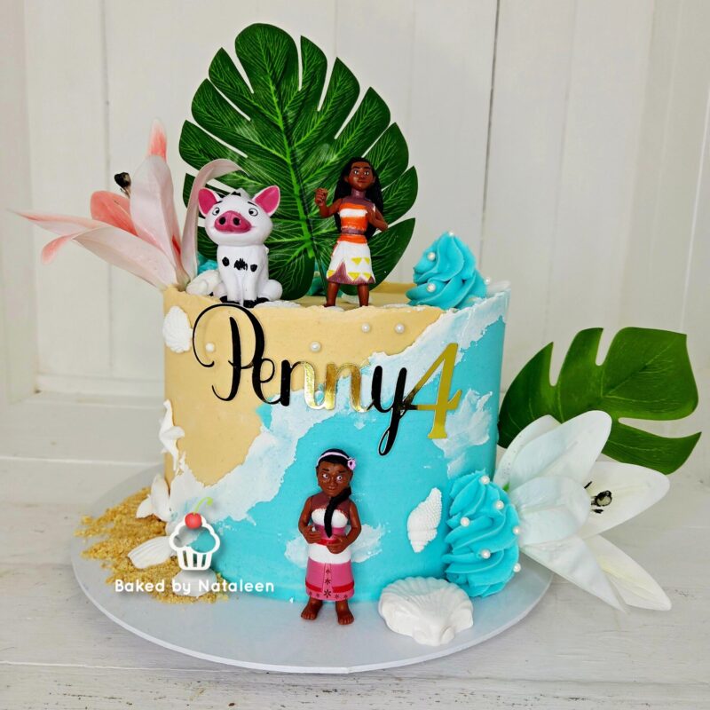 Birthday cake with tropical decorations and Moana-themed fondant figurines, personalized with the name Penny4 on the side.