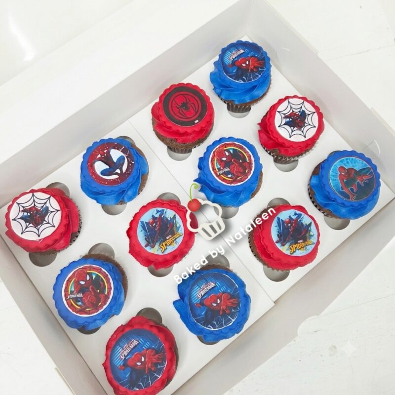 Box of Spider-Man themed cupcakes with red and blue frosting and toppers featuring webs and Spider-Man images