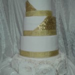 Ornate 4-tier white wedding cake with gold trim - money theme