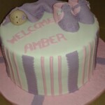 Baby shower cake with pink and purple trim; baby topper with purple blanket and purple and pink booties